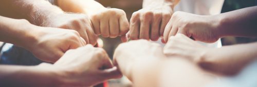 Close up of young people putting their hands together. Team with stack of hands showing unity and teamwork.